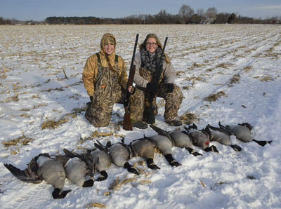 hunters with geese in a field