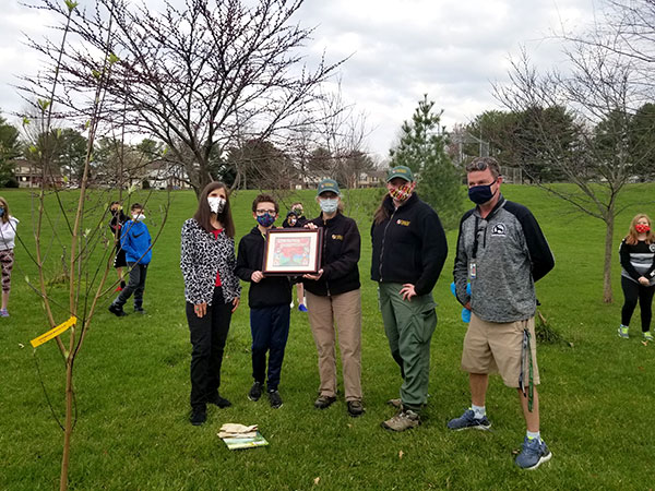 Luke receiving a framed copy of his poster, from the Carroll County Forestry Board during a ceremony at Spring Garden Elementary School