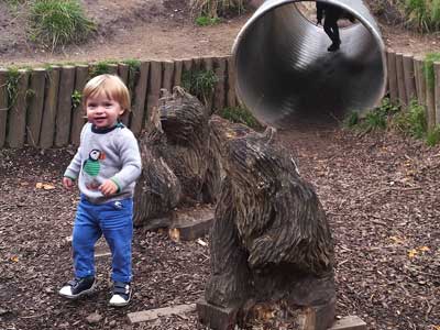 Kid playing by two bears carved from wood