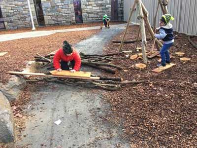 Kids playing with loose tree branches and boards